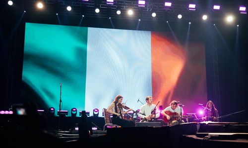 Musicians on a stage infront of an Irish flag