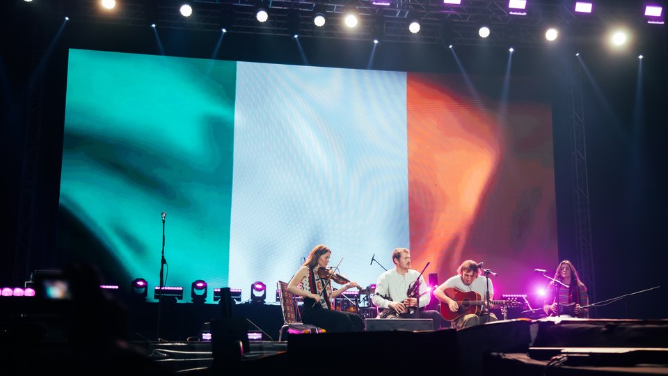 Musicians on a stage infront of an Irish flag