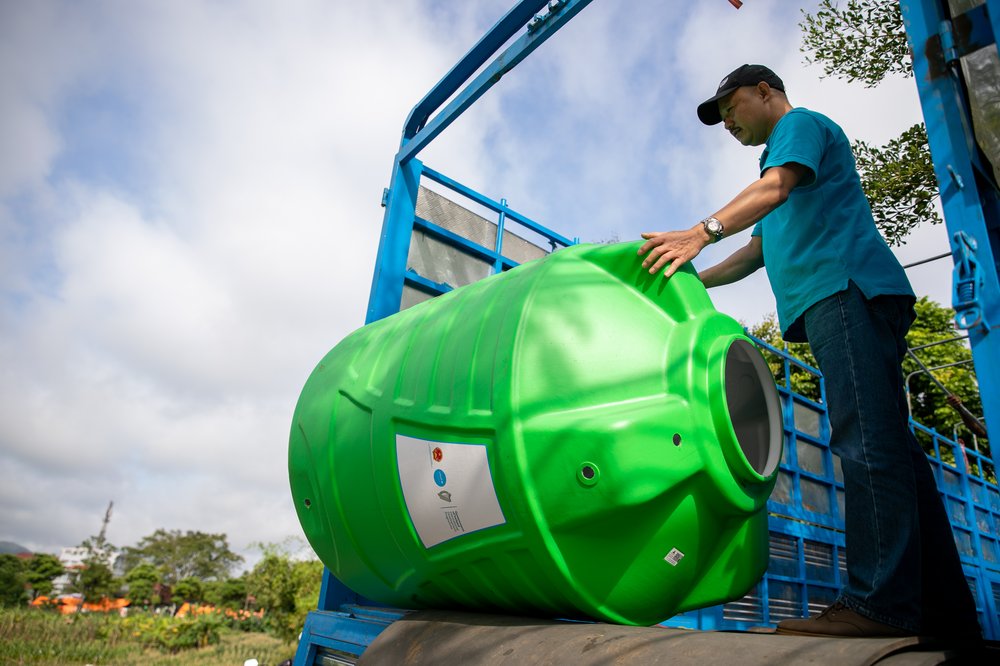 Man pusing green barrel off lorry