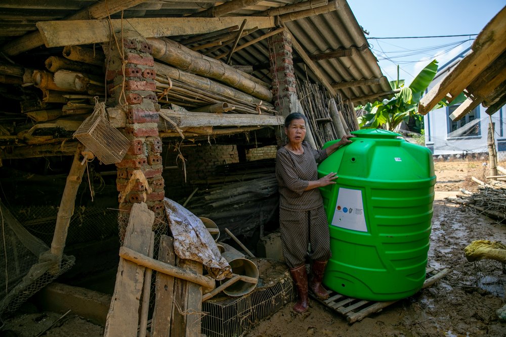 Woman with barrel outside makeshift hut
