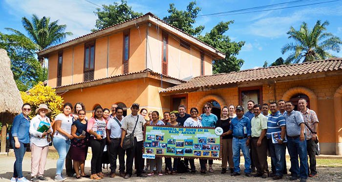 large group of people standing in front of a peach coloured building
