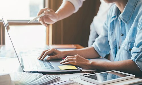 two sets of hands pointing at laptop