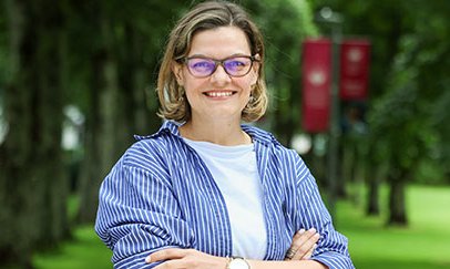 woman outside in front of trees smiling for camera