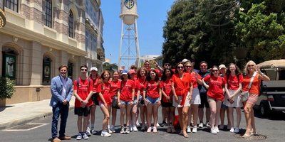 Group photo of students in matching red tshirts with the Warner Brothers tower in the background