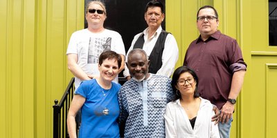 six people standing in front of a yellow doorway on steps