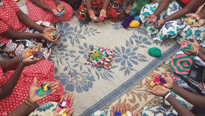 women's hands holding beads for crochet in a circle on a rug