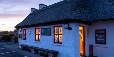 A cottage at dusk, lit warmly from within.