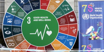 A multicoloured-wheel with test an symbols. In the centre is a line illustration of a heartbeat monitor and heart, with the text: good health and well-being.