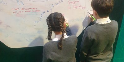 Two children writing on sustainable development wall
