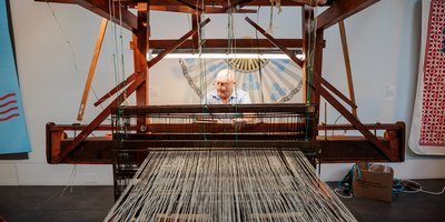 man using a machine to weave tweed