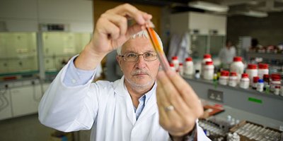 Dr Mike Zaworotko Bernal wears a white lab coat and holds a test tube to the light examining it