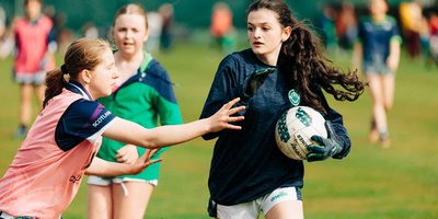 girl with ball about to be tackled by another on a pitch
