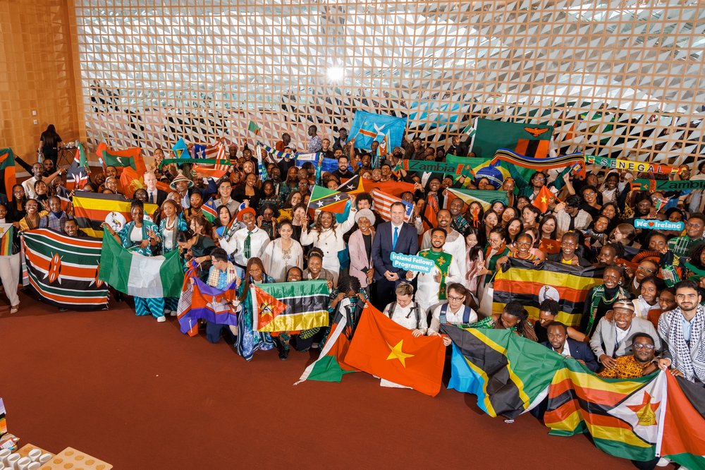 Large group of people in colourful dress waving flags and smiling
