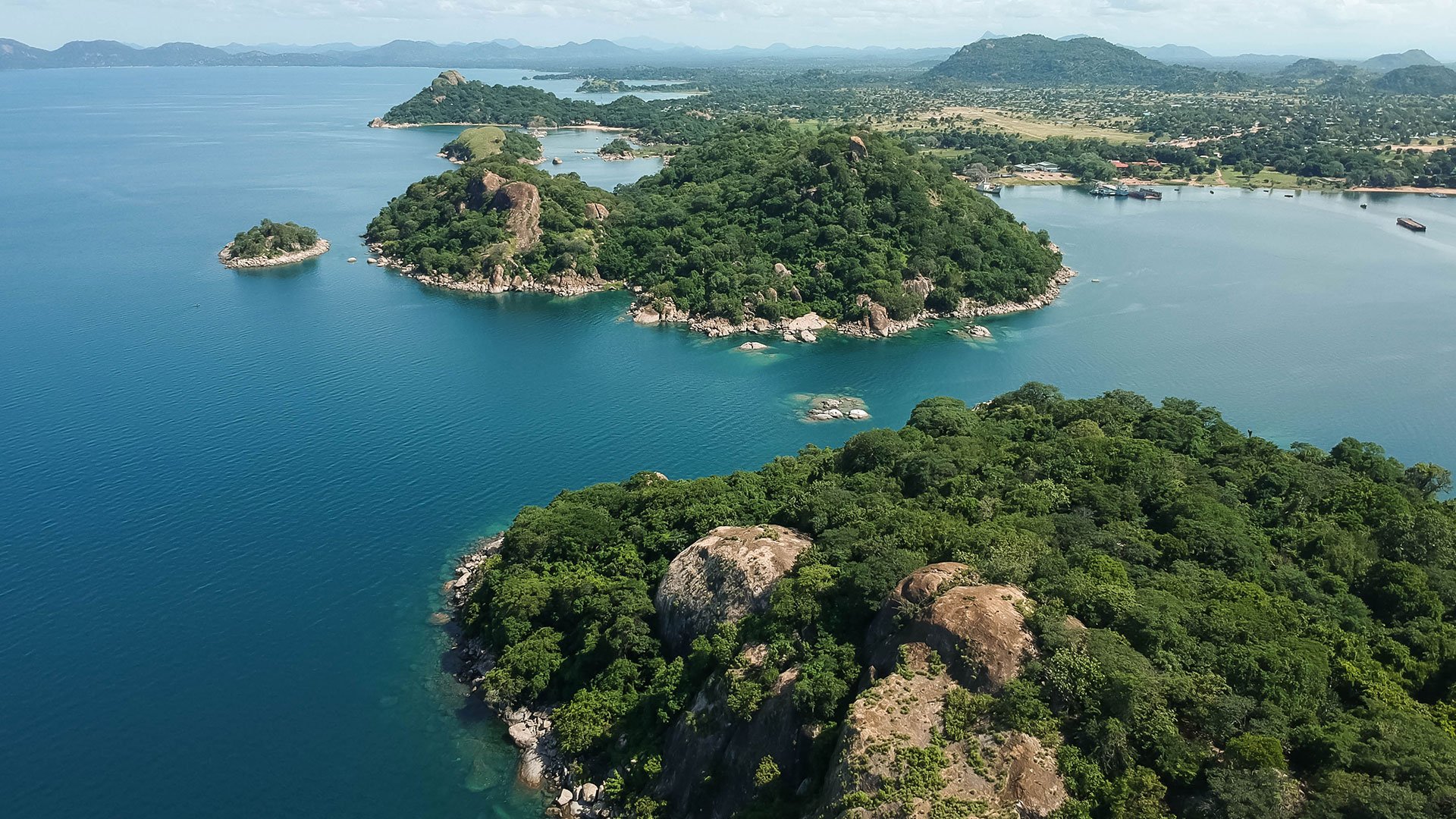 Aerial shot with drone of green mountains and blue water in Monkey Bay, Lake Malawi, Malawi