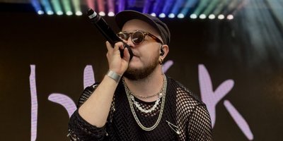 Person singing in front of rainbow lights