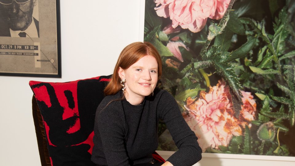 A woman sitting on a chair infront of paintings