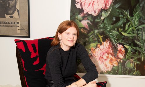 A woman sitting on a chair infront of paintings