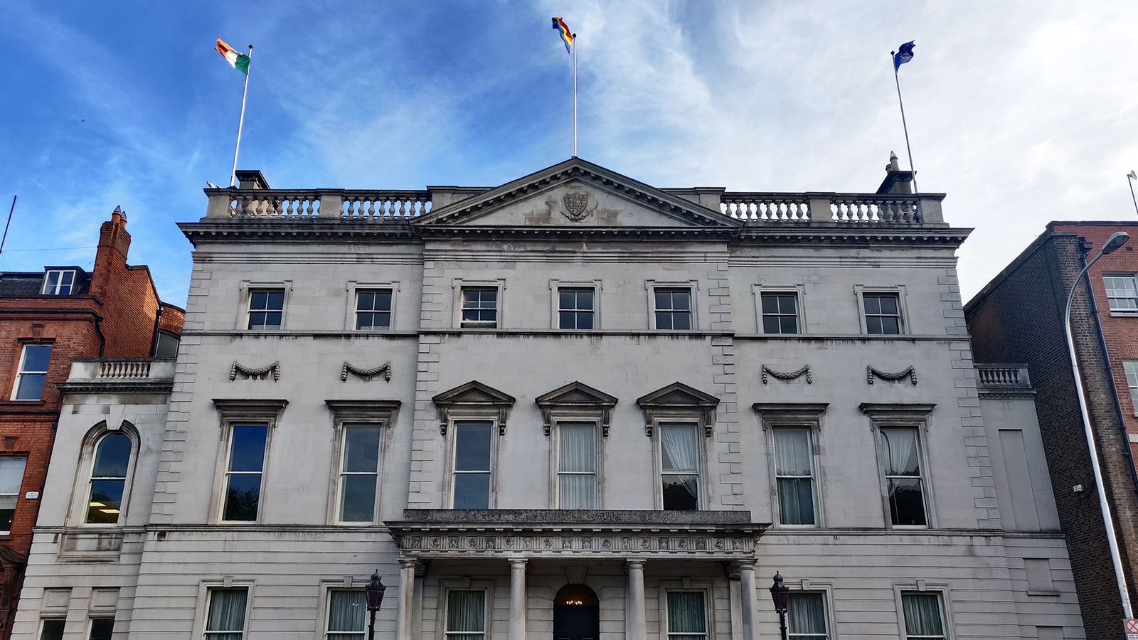 facade of a Georgian building with three floors and seven windows across the top floor, there are three flags on the roof