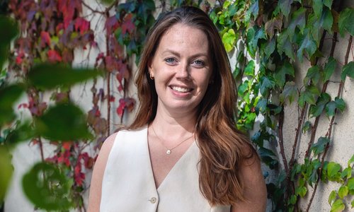 Woman smiling and standing infront of plants