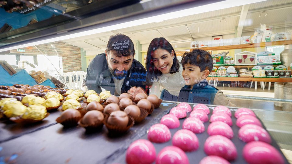 family with two adults and one child looking in a fridge pink, brown and yellow confectionary balls