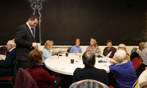 Minister Richmond talking to a group of people at a round table