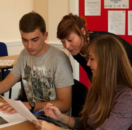 two students at an English language school talking with their teacher who is looking over their shoulders in between them. Photographer George Munday Tourism Ireland