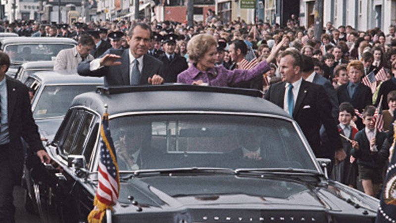 President Richard Nixon in a car with his wife waving to Irish people