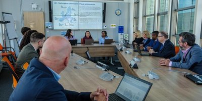 a number of people at a meeting watching a large screen