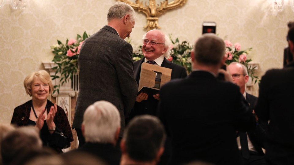 man accepting an award in front of an audience in a lit up room