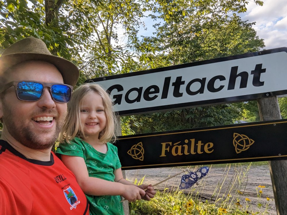 Dónall Ó Dubhghaill with his daughter in front of a Gaeltacht sign