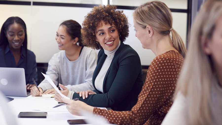 Women sitting at a board table discussing a paper