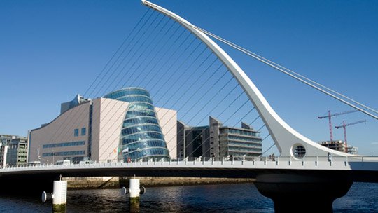 suspension bridge during the day with blue skies and the convention centre in the background