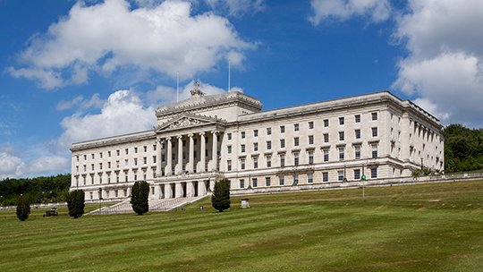 large government building on a hill with lawn in front, blue skies with fluffy clouds