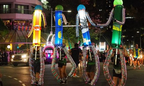 four men carrying robots in a parade at night