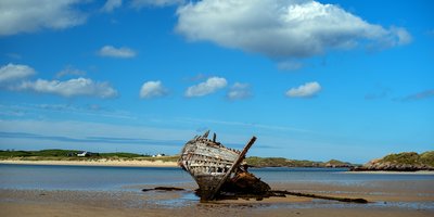 An old rusting shipwreck lying on a beach.