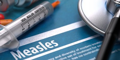 A measles information booklet with a stethoscope, syringe and pills on it