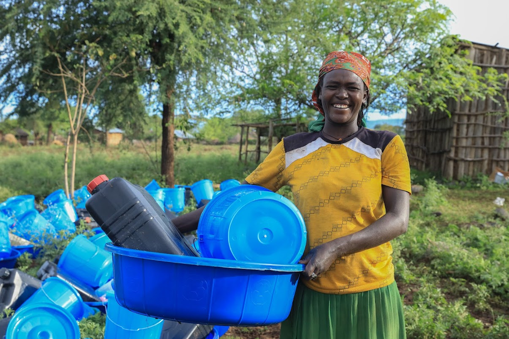 Smiling woman holding plastic basin and barrels