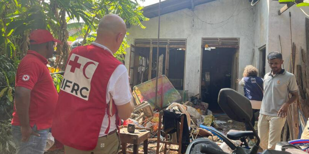 IFRC workers clear up the devastation outside a house