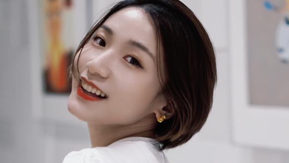 Portrait of a Chinese woman wearing a white shirt looking over her shoulder at camera