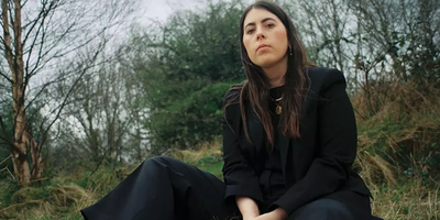 woman dressed in black sitting in a forest