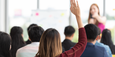 Student in a classroom holding up their hand
